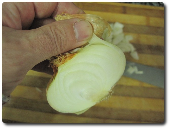 Le retiramos la capa más externa, o las que veamos necesarias para que quede “con buen aspecto”. Tenemos que tener en cuenta que la cebolla concentra sus propiedades cuanto más hacia la capa externa, de ahí que tampoco debemos pasarnos quitando la piel.También le cortamos lo que es la cabeza y la base de las raíces.