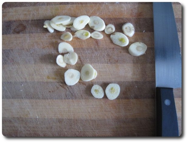 Los cortamos en láminas. Como siempre, después de cortar ajo con el cuchillo, no debemos limpiar éste directamente con un trapo, ni los propios dedos, pues nos quedaría impregnado el olor a ajo para otras cosas que hagamos con el cuchillo, y en las propias manos. Lo mejor es poner el cuchillo y las manos bajo un chorro de agua y mojarlas bien, sin frotar. Simplemente dejar que el agua se escurra por los dedos y el cuchillo.