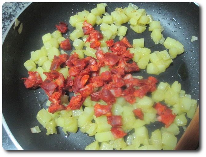 Cuando veamos que la patata ya va cogiendo color de “patata frita” (también podemos probar un trocito a ver que tal), incorporamos el chorizo picado.