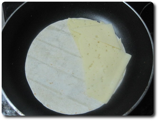 En una de sus mitades vamos a echar el queso. Puede ser en lonchas o rallado. Después de probar con los dos tipos, me parece mejor opción en lonchas, pues ayudará más y mejor a aguantar los ingredientes del relleno en los bordes de la quesadilla, impidiendo mejor que se desparramen. Se pueden usar muchos tipos de queso tipo graso y con sabor, como este Havarti. Los de tipo tranchetes no me parecen apropiados a para esta receta, precisamente por eso, por su falta de sabor. Yo empleé unas dos lochas de havarti por quesadilla.