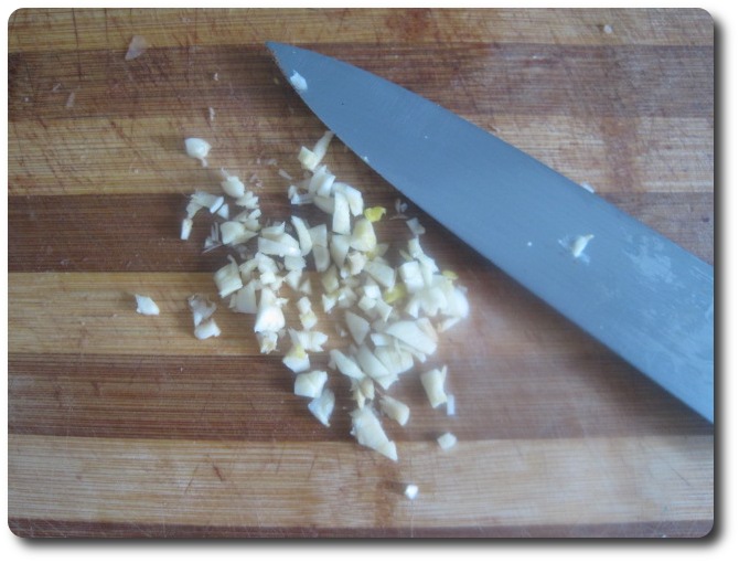 Nos quedará todo picadito. Después de usar el cuchillo para cortar ajo nunca debemos limpiarlo con un trapo, ni las manos tampoco. Ponemos todo, cuchillo y manos, bajo un chorro de agua y mojamos un poco. Echamos el ajo picado en el aceite, para que se vaya calentando.