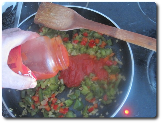 En ese momento, y cuando veamos que la cebolla esté como que transparenta, añadimos al refrito 100 gr. de tomate frito. Si no lo tenéis hecho en casa, es mejor comprar el que venden como 